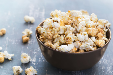 Sweet caramel popcorn in a  bowl on a dark blue background
