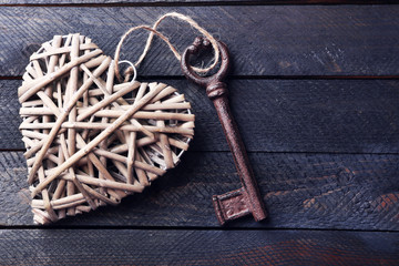 Old key with decorative heart on dark wooden background, close up