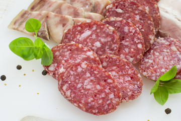 Slices of salami and bacon on a white background
