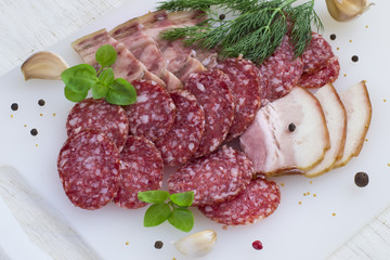 Salami, bacon and greens on a white background