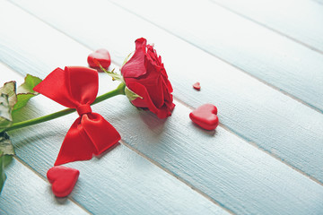 Beautiful rose with small hearts on wooden background