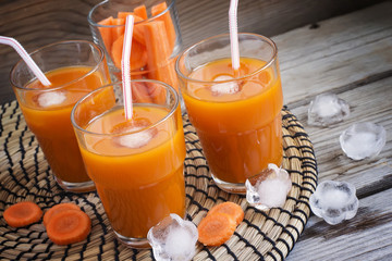 Fresh carrot juice with ice on a wooden background
