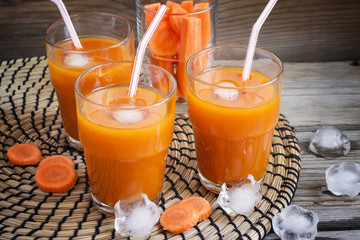 Glasses with carrot juice on a wooden background