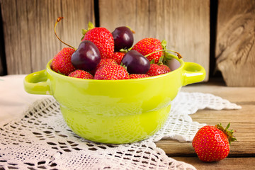 Strawberries and cherries in  bowl on  wooden background