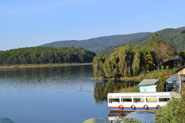 Tuyen Lam lake with boat, house, pine forest and mountain in Dalat, Vietnam 