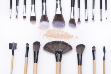 top view of makeup brushes and loose powder on white backgrounds