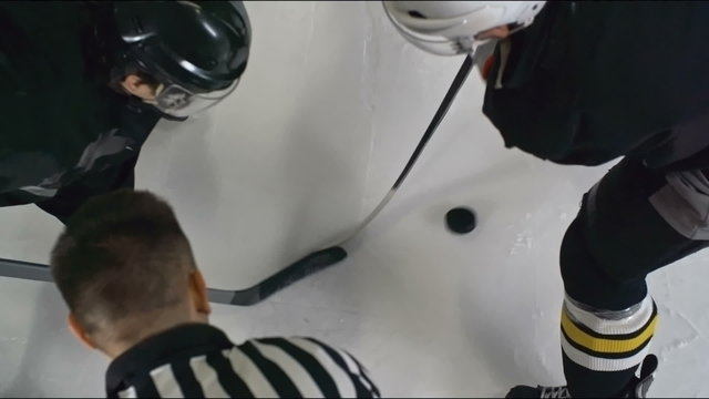 High angle slow motion shot of official dropping a puck during a faceoff 