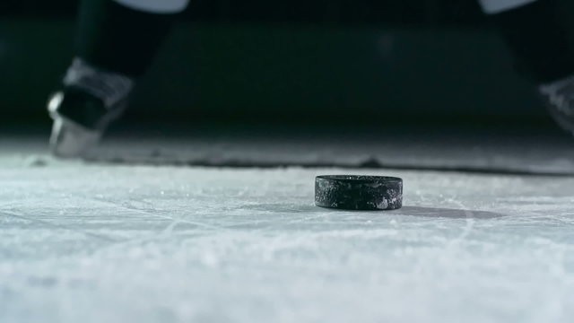 Close-up of hockey puck being struck by hockey player in slow motion