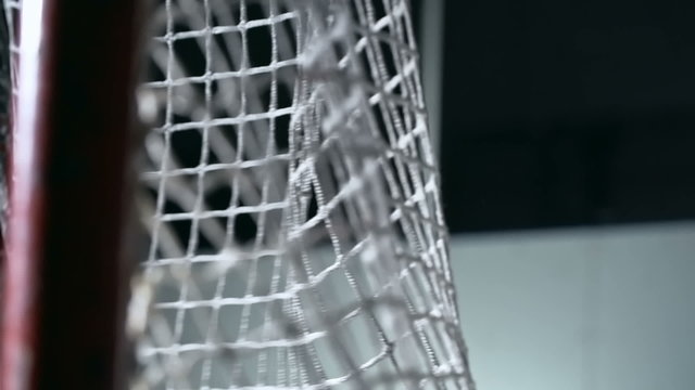 Close-up shot of hockey puck flying into goal and hitting net in slow motion 