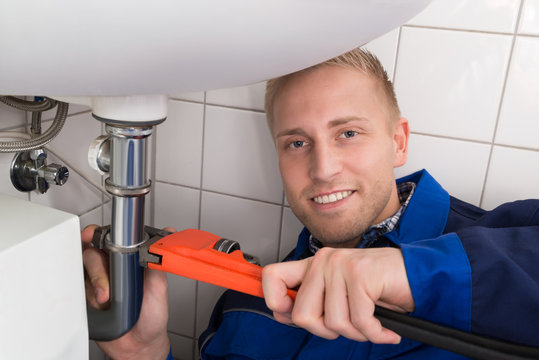 Male Plumber Fixing Sink In Kitchen