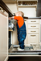 Fototapeta premium Baby helping unload dishwasher