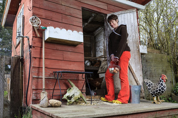 Woman stands outside chicken coop holding eggs in a basket © michaelcourtney