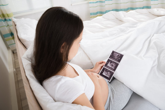 Pregnant Woman Looking At Ultrasound Scan Of Baby