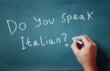 Fototapeta premium the question do you speak italian written on chalkboard and male hand 