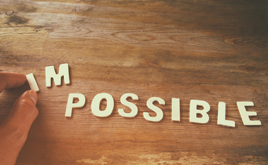 man hand taking of the letters in from the word imposible so it says possible
