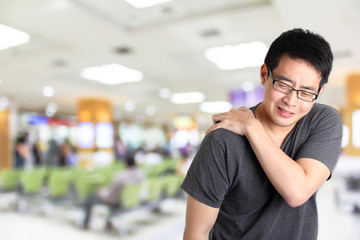 man shoulder pain with blur hospital background