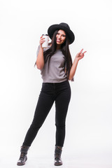 Young attractive woman with rich long brown hair in hat drinking coffee white background.