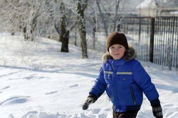 Boy in blue jacket running through the snow