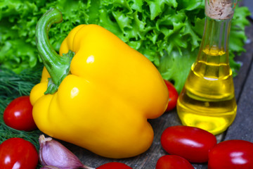 Fresh vegetables. Yellow pepper with red tomatoes and lettuce on a wooden background