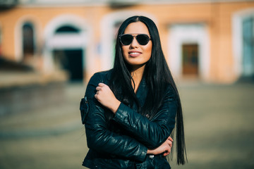 Obraz premium Young fashion brunette woman in sunglasses with jacket on city street. Series of poses.