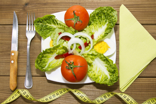 plate of salad and tape measure on wood