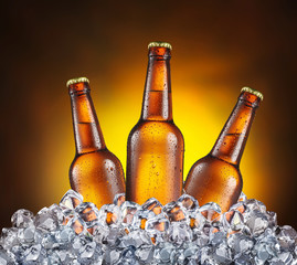 Three bottles of beer in the ice cubes on the yellow background.