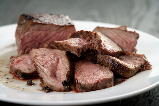 sliced beef steak on white plate on wood table