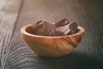 dark chocolate chunks in wooden bowl on table