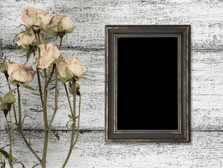 Dry roses and photo frame on background of shabby wooden planks