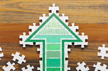 Arrow shaped jigsaw puzzle. Concept image of making growth strategy. Jigsaw puzzle pieces on wooden...