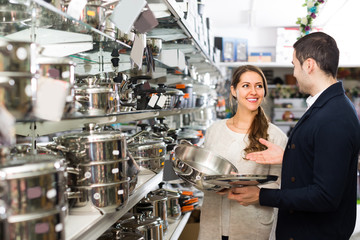 Couple buying pans in shop cookware.