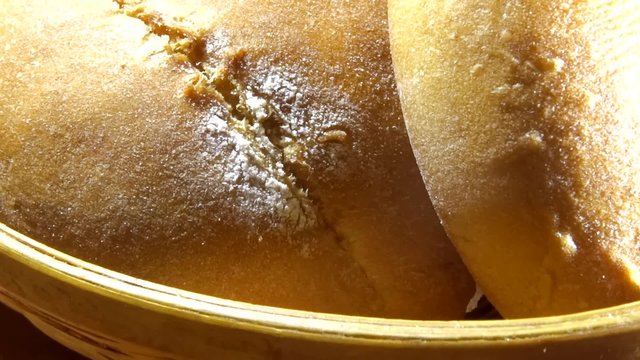 Zoom in and zoom out studio shot of sliced bread and round buns in wicker breadbasket