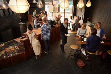 Popular modern coffee shop busy with customers and staff