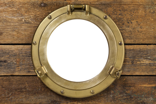 Vintage brass porthole in wooden wall isolated with clipping path