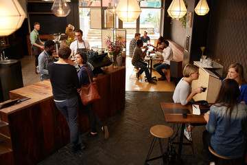 Customers waiting at counter in a busy modern coffee shop