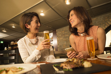 Two women are enjoying a meal in the restaurant while drinking beer