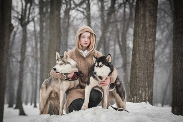 A teen girl with two husky dogs 
