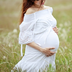 Beautiful pregnant woman in a camomile field 