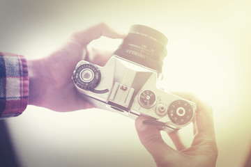Hands holding vintage analog camera with retro filter