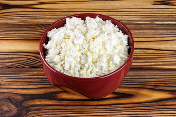 Fresh cottage cheese in ceramic bowl on wooden table