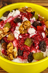 Sweet cottage cheese dessert with raspberry jam, nuts, raisins, candied in ceramic bowl on wooden table, selective focus