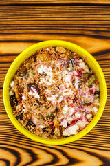 Sweet cottage cheese dessert with raspberry jam, dried fruits, grated chocolate in bowl on wooden table, top view
