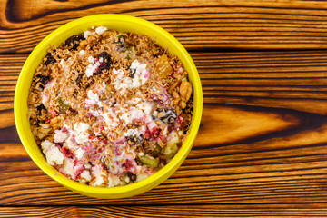 Sweet cottage cheese dessert with raspberry jam, dried fruits, grated chocolate in bowl on wooden table, top view