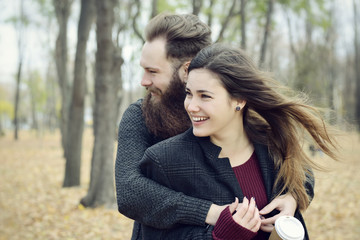 Fashion portrait of young couple drinking coffee in autumn park