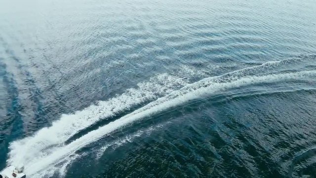 Aerial view of a fast fishing boat speeding in clean blue water 