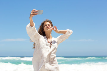 Fun young woman taking selfie at seaside