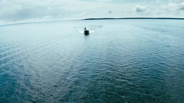 Aerial view of a fast fishing boat speeding in clean blue water 