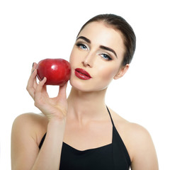 Portrait of beautiful young woman holding red apple near her fac