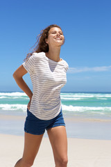 Smiling young woman in shorts walking on the beach