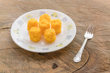 Sweet egg floss in a dish with fabric on wood background kind of Thailand traditional dessert in thai name of Foi Thong
